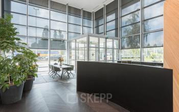 Ruime en lichte entree van een kantoorpand aan de Brandweerstraat 20-30, Enschede, met grote ramen en een moderne uitstraling. De ruimte is ingericht met een ontvangstbalie en zitgelegenheid.