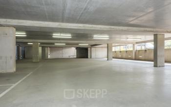Ruime parkeergarage van het kantoorpand aan Brandweerstraat 20-30, Enschede, ideaal voor bedrijven die kantoorruimte willen huren met parkeerfaciliteiten. Betonvloer en goede verlichting aanwezig.