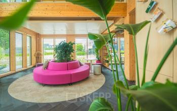 Moderne kantoorruimte huren op Moutlaan 1-23 in Enschede, met houten interieur en kleurrijke zithoek. Geschikt voor huur voor diverse zakelijke activiteiten.
