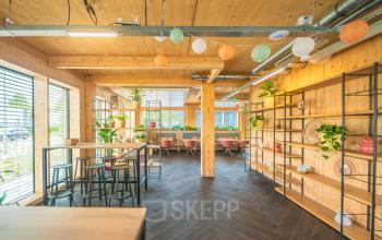 Lichte kantoorruimte huren op Moutlaan 1-23 in Enschede met een moderne, warme uitstraling, houten accenten en speelse decoratie. Ideaal voor flexibele werkplekken in een inspirerende omgeving.