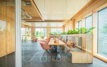 Licht en modern ingerichte kantoorruimte met houten accenten en planten aan Moutlaan 1-23, Enschede. Ideaal voor wie op zoek is naar een inspirerend kantoor om te huren.