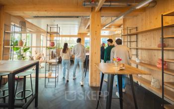 Moderne kantoorruimte huren op Moutlaan 1-23, Enschede, met een lichte inrichting en houten elementen. Mensen voeren zakelijke activiteiten uit in een gemeubileerd interieur.