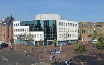 Kantoorpand aan Hoedemakerplein 2, Enschede met moderne glazen gevels en stedelijke omgeving, ideaal voor kantoorruimte huren.