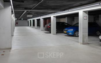 Ondergrondse parkeergarage in kantoorpand op Kuipersdijk 2-4, Enschede met betonnen muren en meerdere geparkeerde auto's.