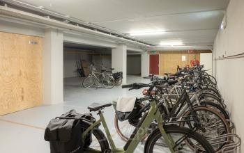 Fietsenstalling in het kantoorpand op Kuipersdijk 2-4 in Enschede, met diverse fietsen geparkeerd tegen een muur. Ideale faciliteit bij het kantoorruimte huren.