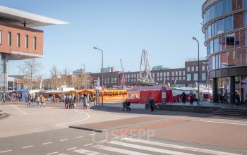 Buitengezicht van Kuipersdijk 2-4 in Enschede, met kantoorruimtes omringd door stedelijke activiteit en voetgangers.