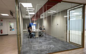 Vergaderruimte in modern kantoorpand op Kuipersdijk 2-4 in Enschede met mensen die een zakelijke bespreking houden.