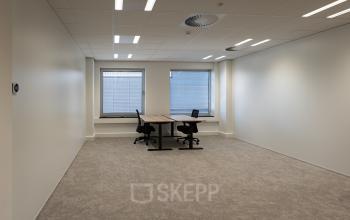 Lichte kantoorruimte met twee bureaus en stoelen, gelegen op Kuipersdijk 2-4 in Enschede, beschikbaar om te huren.