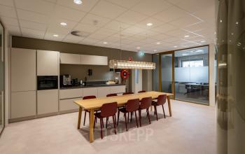 Moderne keuken in kantoorpand op Kuipersdijk 2-4, Enschede met ruime tafel en stoelen, ideaal voor huur als werkruimte.