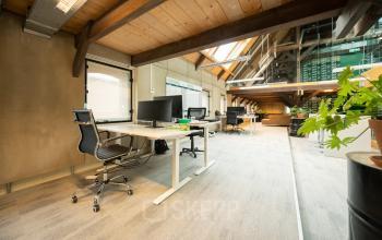 Kantoorruimte huren in Franeker aan de Prins Hendrikkade 3 met een moderne, open indeling. Voorzien van werkstations met bureaustoelen en computerschermen onder een rustiek houten plafond.