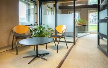 Kantoorruimte huren op Prins Hendrikkade 3 in Franeker met moderne inrichting, inclusief glazen wanden, houten stoelen en groene planten, geschikt voor diverse werkdoeleinden.