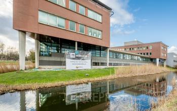 Exterieur van het kantoorpand op Tielweg 30 in Gouda, met moderne architectuur en omringd door groen en een waterpartij. Perfecte locatie voor kantoorruimte huren.