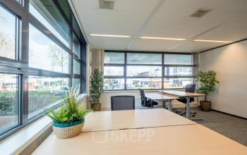 Binnenkant van kantoorpand aan Tielweg 30 in Gouda met grote ramen, comfortabele bureaus, planten en heldere verlichting. Ideaal voor kantoorruimte huren met uitzicht op buitenomgeving.