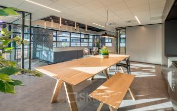 Moderne kantoorruimte aan de Tielweg 30 in Gouda, gevuld met stijlvolle houten tafels en planten, ideaal voor creatieve werksessies. Perfect voor wie op zoek is naar een inspirerende plek om te huren.