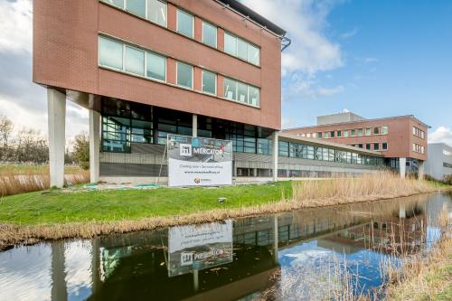 Exterieur van het kantoorpand op Tielweg 30 in Gouda, met moderne architectuur en omringd door groen en een waterpartij. Perfecte locatie voor kantoorruimte huren.