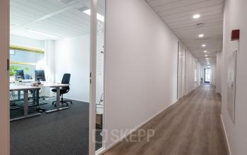 Moderne kantoorruimte in Gouda met glazen deur en een lichte werkplek met bureau en computerschermen, gelegen aan Groningenweg 8 8.