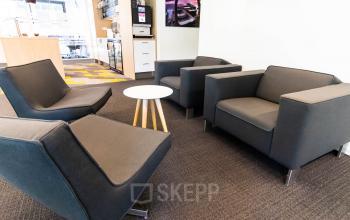 Moderne kantoorruimte te huur op Kampenringweg 45 in Gouda, voorzien van comfortabele zwarte zitbanken en een witte bijzettafel, met zicht op een open keuken en kantoorfaciliteiten.