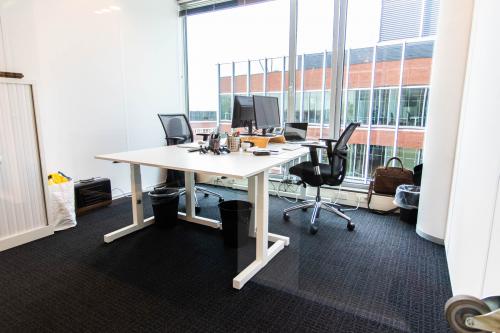 Modern kantoorruimte huren in Gouda met grote ramen, twee bureaus, bureaustoelen, en computers, ideaal voor professioneel werken.