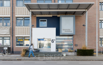 Het exterieur van het kantoorpand op Atoomweg 6B in Groningen, met een moderne glazen entree. Mensen lopen langs de ingang.