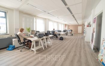 Binnenzicht van een open kantoor op Atoomweg 6B in Groningen met werknemers aan bureaus, ruime werkplekken en veel natuurlijk licht.