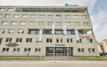 Exterieur van kantoorpand op Leonard Springerlaan 7, Groningen; geschikt voor kantoorruimte huren met meerdere verdiepingen en moderne uitstraling. Toegang via brede ingang met vlaggen aan de voorzijde.