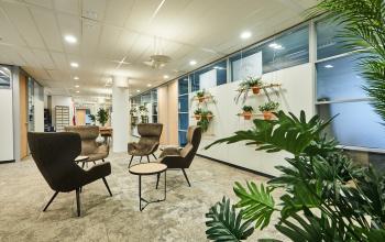 Stijlvol ingerichte kantoorruimte met moderne zitgedeelte en veel groen, ideaal voor het huren van een comfortabele werkplek op Leonard Springerlaan 7, Groningen.