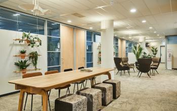 Kantoorruimte huren aan Leonard Springerlaan 7 in Groningen, met moderne inrichting, comfortabele zitplekken, en grote tafel, omringd door planten. Zakelijke activiteit in een uitnodigende sfeer.