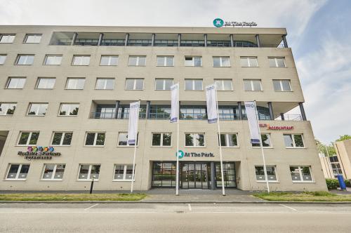 Exterieur van kantoorpand op Leonard Springerlaan 7, Groningen; geschikt voor kantoorruimte huren met meerdere verdiepingen en moderne uitstraling. Toegang via brede ingang met vlaggen aan de voorzijde.