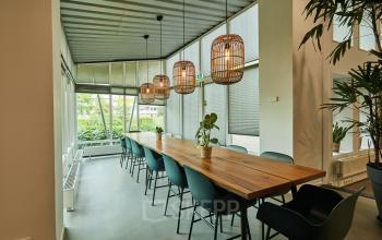Ruime, moderne kantoorpand met grote tafel en stoelen, veel natuurlijk licht door grote ramen, ideaal voor kantoorruimte huren aan de Friesestraatweg in Groningen.