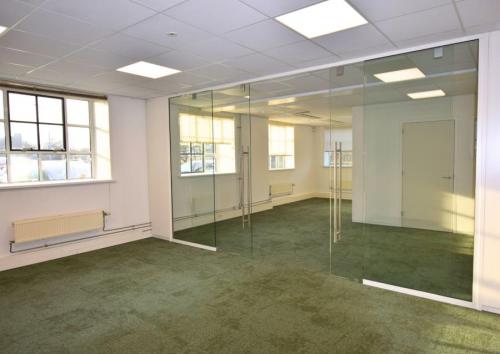Lichte kantoorruimte met groene vloerbedekking en glazen wanden op de Friesestraatweg 207-221 in Groningen, ideaal om een eigen kantoor te huren.