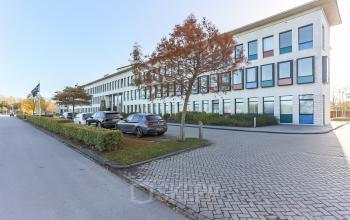 Uitzicht op het kantoorpand op Zernikepark 12 in Groningen. Een moderne witte gevel met grote ramen en een parkeerplaats aan de voorkant.
