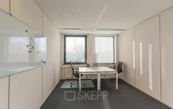 Kantoorruimte huren in Groningen: licht kantoor met twee bureaus en stoelen, grote ramen en een whiteboard, ideaal voor vergaderingen of individuele werksessies.