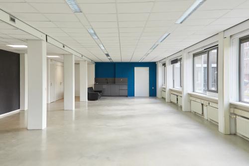 Lichte kantoorruimte te huur op de Schweitzerlaan 12, Groningen met grote ramen en een kleine keukenblok aan de zijkant.