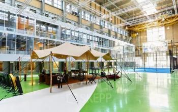 Brede binnenruimte op Helperpark 270-298 in Groningen met een sportveld, tentachtige structuren en meerdere personen die werken en ontspannen.