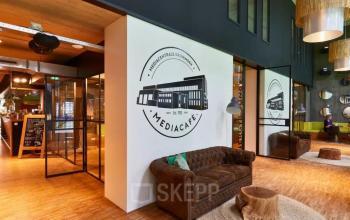 Sfeervolle entree van het Mediacafé in Groningen met stijlvolle meubels, geschikt voor informeel overleg.