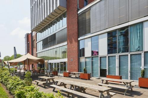 Buitenzijde van een kantoorpand gelegen aan Helperpark 270-298 in Groningen, voorzien van houten picknickbanken en een overkapping op een ruim terras.
