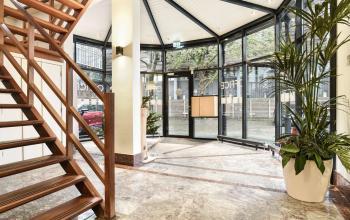 Moderne entreehal van een kantoorpand op Kennemerplein 20, met hoge glazen wanden, marmeren vloeren en een stijlvolle houten trap.