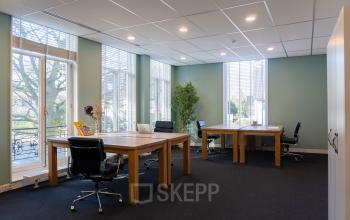 Modern ingerichte kantoorruimte met natuurlijk licht en uitzicht op Kennemerplein 20, Haarlem Centraal Station, voorzien van houten bureaus en comfortabele bureaustoelen.