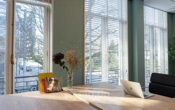 Modern ingerichte kantoorruimte op Kennemerplein 20, Haarlem Centraal Station met veel daglicht, een bureau, laptop en comfortabele stoel.