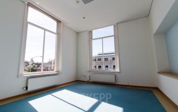 Ruime kantoorruimte huren op Prinsen Bolwerk 1, Haarlem, met groot raam en uitzicht op de stad. Veel daglicht valt naar binnen, ideaal voor een inspirerende werkplek.