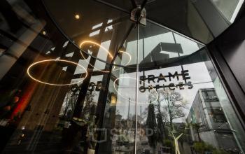 Revolverende glazen deur van kantoorpand Kennemerplein 6-14, Haarlem Centraal Station, weerspiegelingen van de straat zichtbaar in de ramen. Kantoorruimte huren met moderne uitstraling.