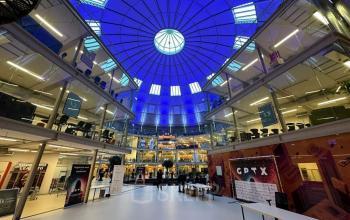 Ruim, modern kantoorpand met glazen dak op Koepelplein 1E, Haarlem Centrum. Mensen zijn bezig met zakelijke activiteiten. Perfecte locatie voor kantoorruimte huren in een dynamische werkomgeving.