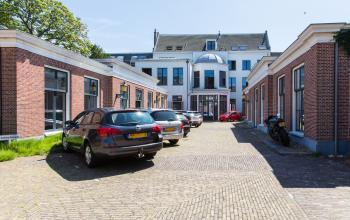 Exterieur van het kantoorpand aan de Nieuwe Gracht 74-76 in Haarlem Centrum, omgeven door stenen gebouwen en geparkeerde auto's.