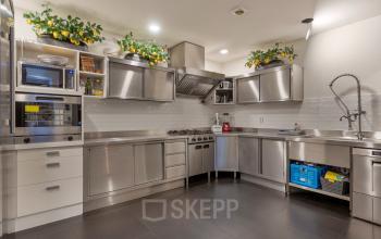 Moderne keukenruimte met roestvrijstalen apparatuur en decoratieve citroenplanten, Grote Houtstraat 176-180, Haarlem Centrum, kantoorruimte huren.