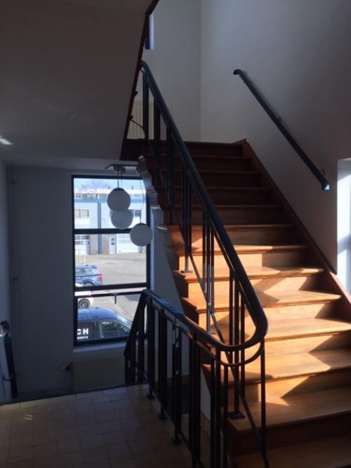 Binnenaanzicht van een trappenhuis in een kantoorpand aan de Nijverheidsweg 50, Haarlem Oost. Hout en eenvoudige leuningontwerpen stralen een functionele sfeer uit.