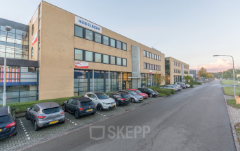 Modern ogend kantoorpand aan Mollerusweg 84 in Haarlem Waarderpolder, met een gevulde parkeerplaats voor het gebouw.