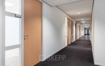 Gang in het kantoorpand op Mollerusweg 84 in Haarlem Waarderpolder, ideaal voor kantoorruimte huren. De gang heeft deuren aan beide zijden en biedt toegang tot verschillende kantoren.