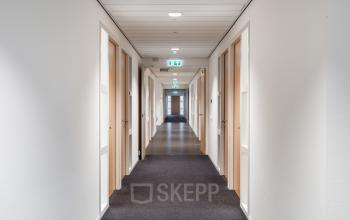 Lange gang in een kantoorpand met witte muren en meerdere gesloten deuren aan beide zijden op Mollerusweg 84, Haarlem Waarderpolder.