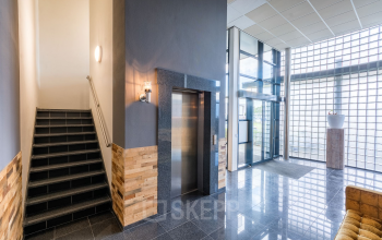 Trappenhuis en lift in de kantoorruimte op Mollerusweg 84, Haarlem Waarderpolder. Moderne afwerking met glazen wanden en tegelvloer.
