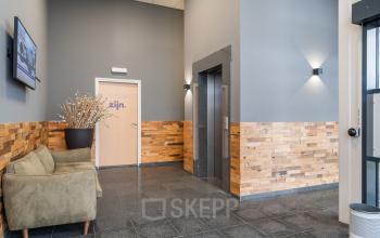 De entree van een kantoorpand op Mollerusweg 84, Haarlem Waarderpolder, met moderne houten afwerking en comfortabele zitgelegenheid. Ideaal voor kantoorruimte huren met een uitnodigende sfeer.
